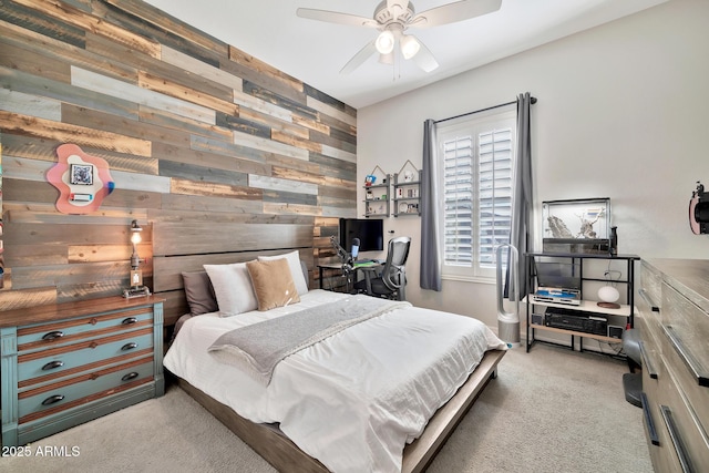 bedroom featuring ceiling fan, light carpet, and wooden walls