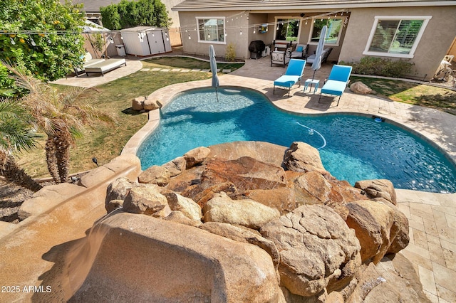 view of pool featuring a patio and a storage shed