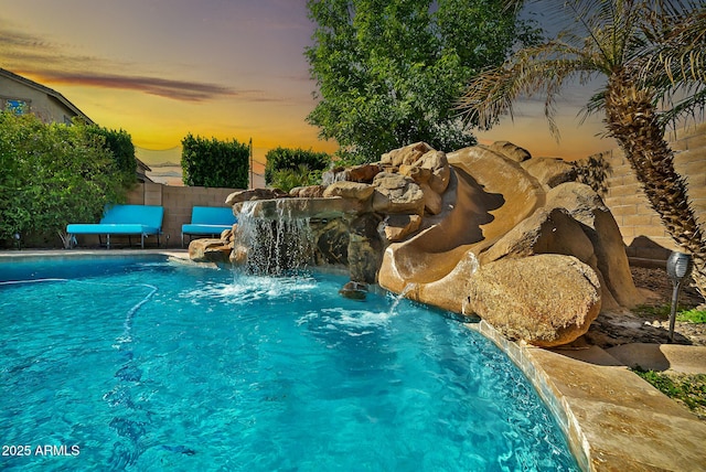 pool at dusk featuring pool water feature