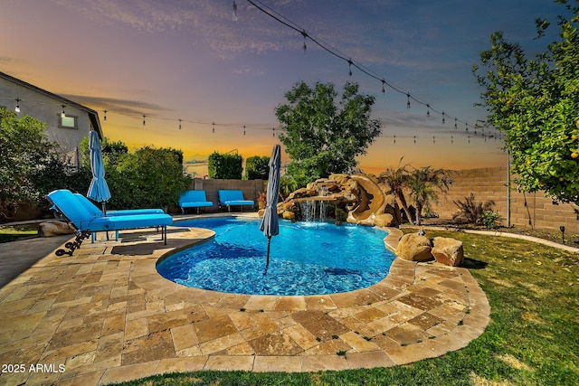 pool at dusk with a water slide and a patio