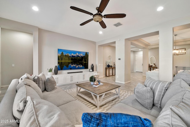 tiled living room with ceiling fan with notable chandelier