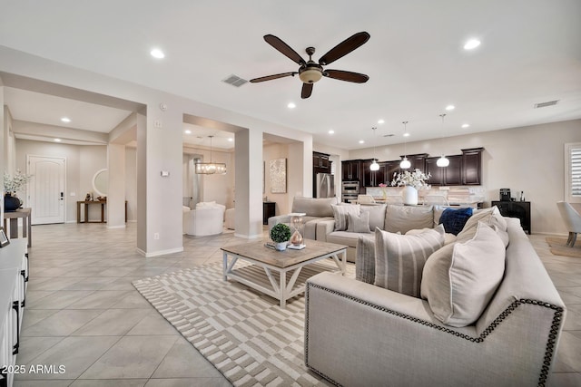 living room with ceiling fan with notable chandelier and light tile patterned floors