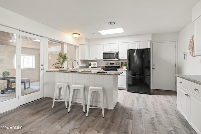 kitchen with appliances with stainless steel finishes, a kitchen bar, and white cabinets