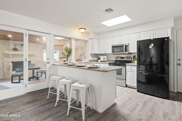 kitchen with appliances with stainless steel finishes, sink, white cabinets, and light hardwood / wood-style floors