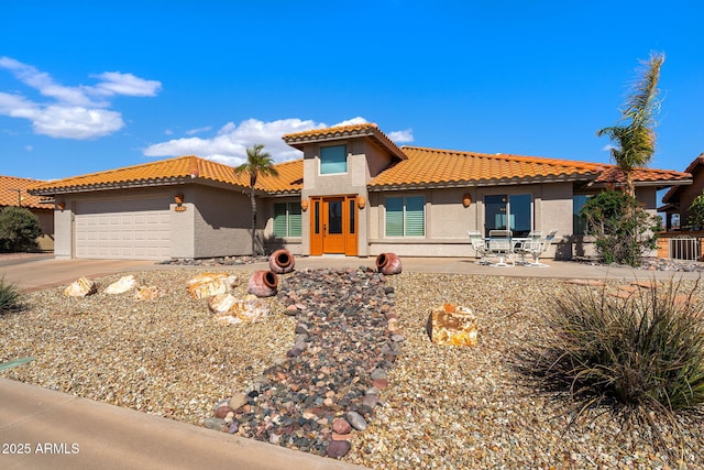 mediterranean / spanish home featuring a garage, driveway, a tiled roof, and stucco siding