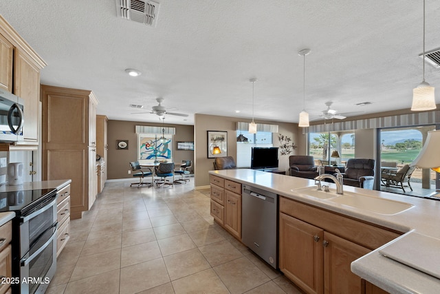 kitchen featuring light tile patterned flooring, a sink, visible vents, open floor plan, and appliances with stainless steel finishes