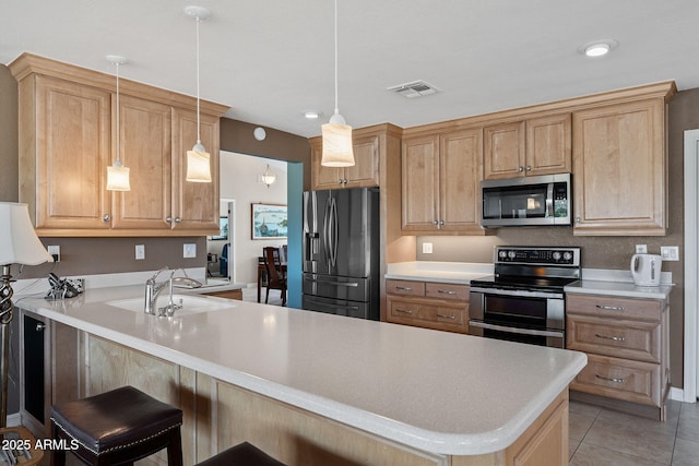 kitchen with visible vents, appliances with stainless steel finishes, a peninsula, light countertops, and a sink