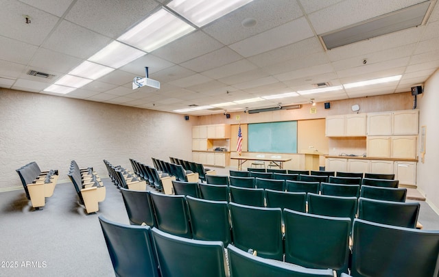 cinema featuring a textured wall, a paneled ceiling, and visible vents