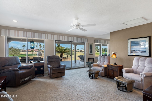 living room featuring ceiling fan, a textured ceiling, carpet flooring, and a textured wall