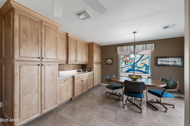 kitchen featuring light tile patterned floors, visible vents, baseboards, ceiling fan, and backsplash