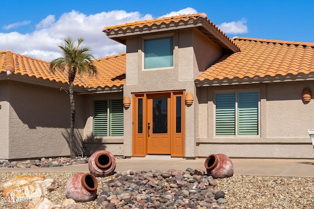 view of front facade with a tiled roof and stucco siding