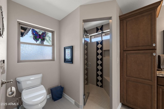 bathroom featuring a stall shower, tile patterned flooring, baseboards, and toilet