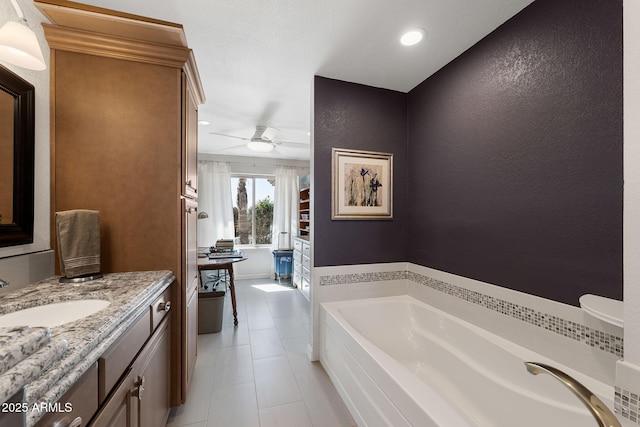 bathroom featuring a textured wall, ceiling fan, tile patterned floors, a garden tub, and vanity