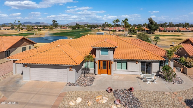 mediterranean / spanish-style home featuring a garage, concrete driveway, a tiled roof, a mountain view, and stucco siding