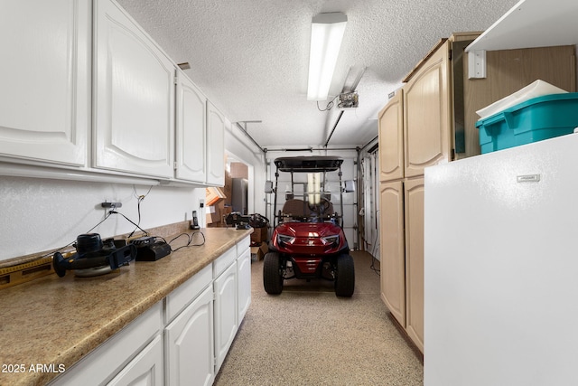 kitchen with light countertops, freestanding refrigerator, white cabinets, and a textured ceiling