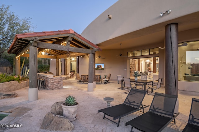 patio terrace at dusk featuring a gazebo and exterior bar