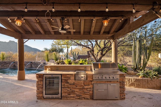 view of patio / terrace with a mountain view, ceiling fan, exterior kitchen, wine cooler, and area for grilling