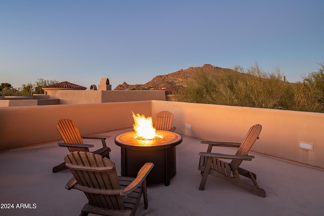 patio terrace at dusk featuring a mountain view and an outdoor fire pit