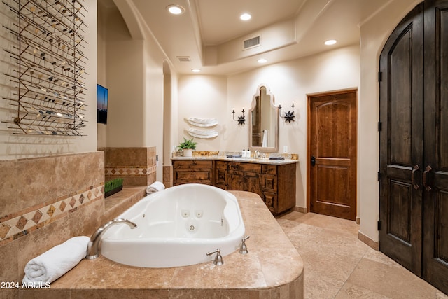 bathroom with tiled tub and vanity