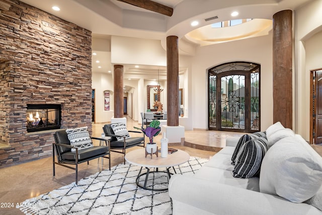 living room with a fireplace, a towering ceiling, and decorative columns