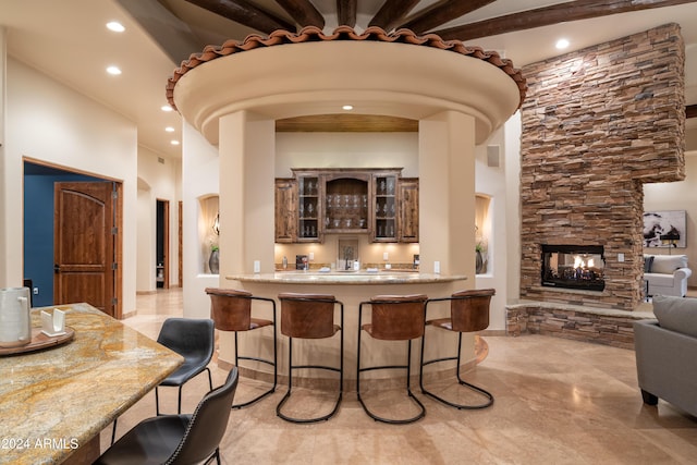 bar featuring a towering ceiling and a stone fireplace