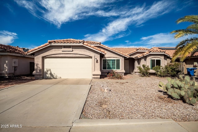 mediterranean / spanish house with a garage, driveway, a tile roof, and stucco siding