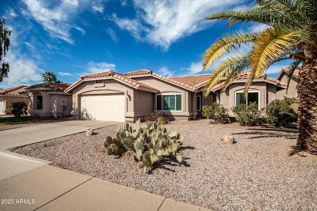 view of front of home with a tile roof, driveway, an attached garage, and stucco siding