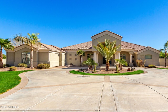 mediterranean / spanish-style home featuring curved driveway, a tile roof, and stucco siding