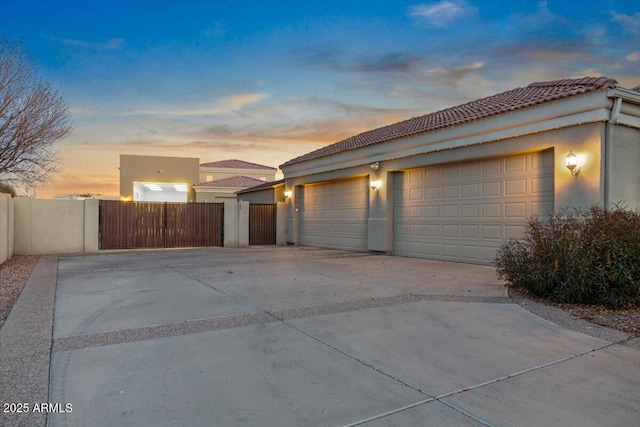 garage with concrete driveway, fence, and a gate