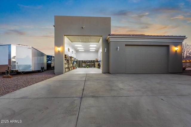 view of front of house with an attached garage, a tiled roof, concrete driveway, and stucco siding