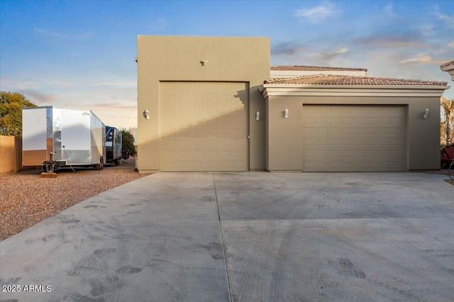 exterior space featuring driveway, a tiled roof, and stucco siding