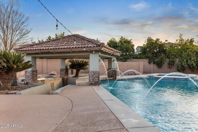 view of pool with a pool with connected hot tub, area for grilling, a gazebo, a patio area, and fence