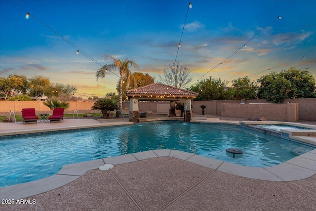 view of swimming pool with a patio area, a fenced backyard, a pool with connected hot tub, and a gazebo