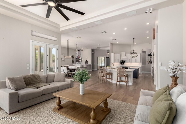 living room featuring arched walkways, recessed lighting, visible vents, french doors, and light wood finished floors