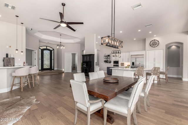 dining area featuring a tray ceiling, light wood-type flooring, visible vents, and baseboards