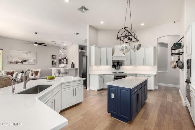 kitchen featuring a center island, blue cabinetry, visible vents, white cabinetry, and a sink