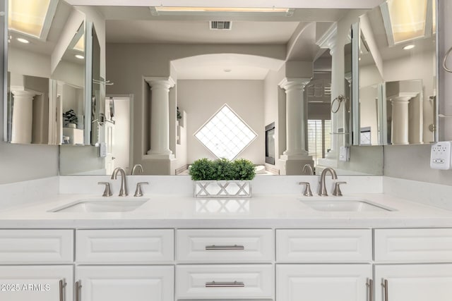 bathroom with visible vents, decorative columns, a sink, and double vanity