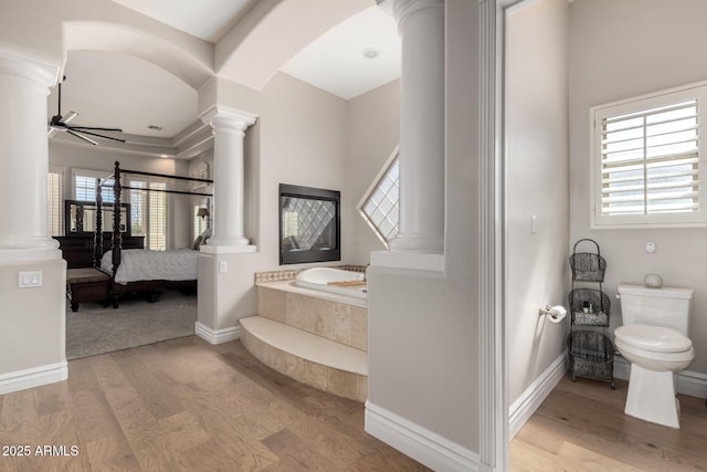 bathroom featuring a wealth of natural light, ornate columns, and wood finished floors