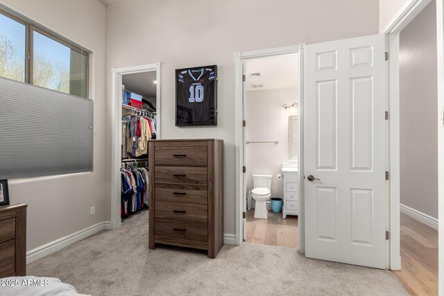 bedroom featuring carpet floors, a closet, a spacious closet, connected bathroom, and baseboards