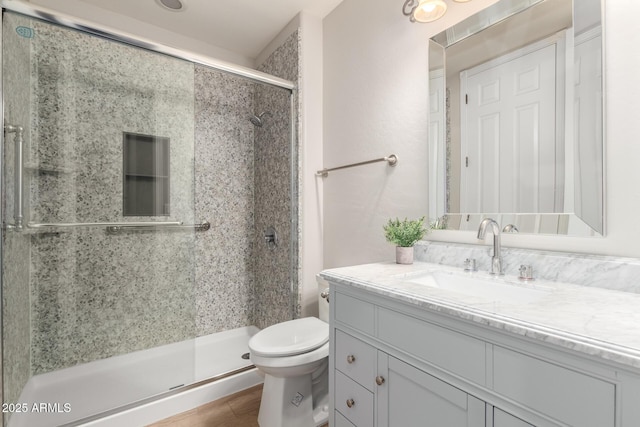 full bathroom featuring toilet, a stall shower, wood finished floors, and vanity