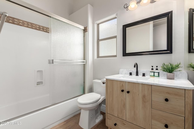 bathroom featuring toilet, enclosed tub / shower combo, and vanity