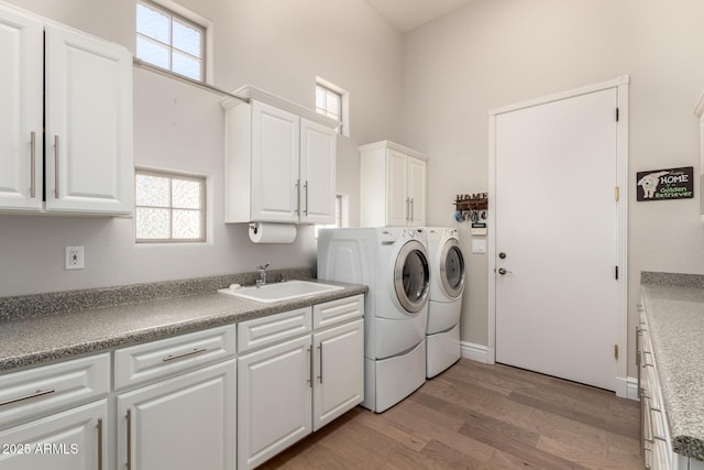 clothes washing area featuring separate washer and dryer, light wood-style flooring, a sink, and a wealth of natural light