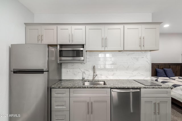 kitchen featuring tasteful backsplash, dark stone counters, appliances with stainless steel finishes, a sink, and recessed lighting