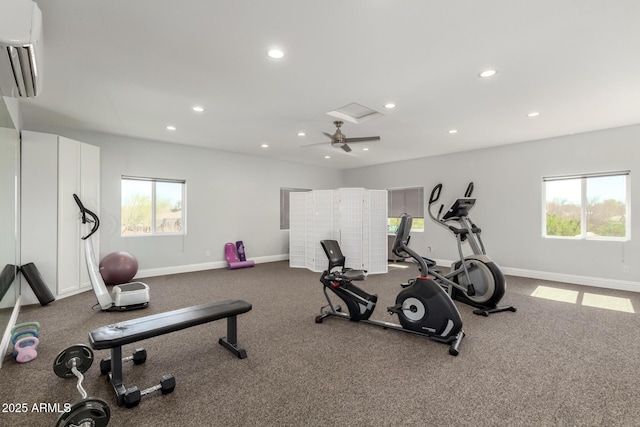 workout room featuring a wall mounted air conditioner, a wealth of natural light, and baseboards