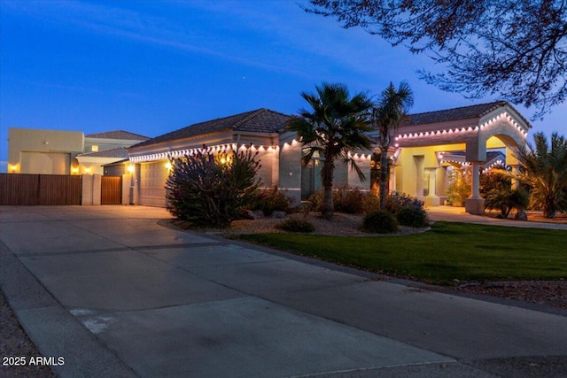 view of front facade featuring driveway, a garage, fence, a front lawn, and stucco siding