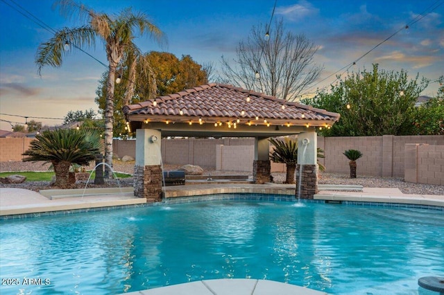 pool at dusk featuring a fenced in pool, a fenced backyard, and a gazebo