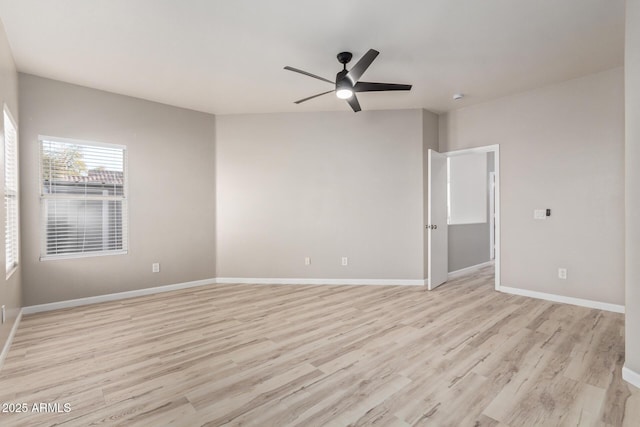 spare room with light wood-type flooring, a ceiling fan, and baseboards