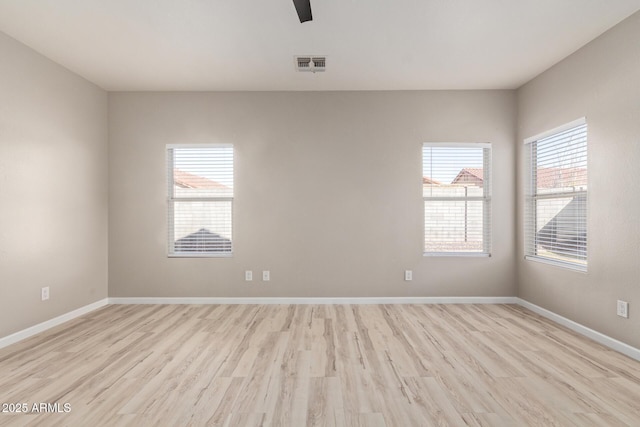 spare room with baseboards, plenty of natural light, visible vents, and light wood-style floors