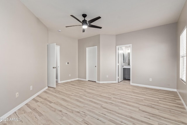 unfurnished bedroom featuring light wood finished floors, ensuite bath, baseboards, and a ceiling fan