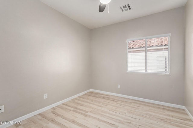 empty room featuring a ceiling fan, visible vents, light wood finished floors, and baseboards